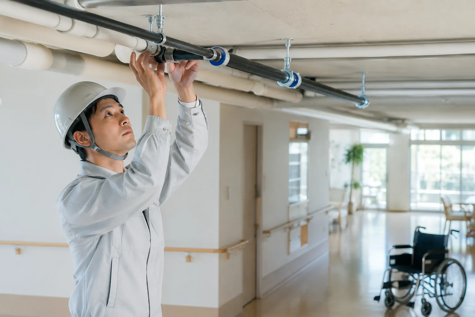 介護施設で配管を点検する作業員のイメージ